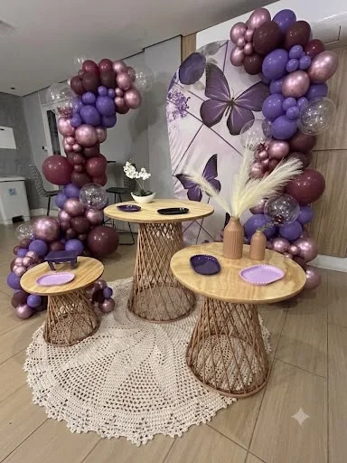 Decoração da Cintia Paula com borboletas, balões em tons de lilás e mesas de fibra natural